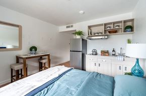 Centralia apartment for rent - A bedroom with a bed, a table, and a refrigerator.