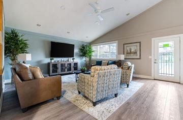 Mukilteo apartment for rent - A living room with a brown leather couch, a patterned armchair, and a television mounted on the wall.