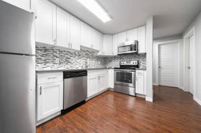 Seattle apartment for rent - A kitchen with white cabinets and a stone backsplash.