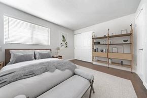 Seattle apartment for rent - A bedroom with a bed, a bench, and a shelf with items on it.
