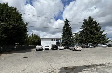 Tacoma apartment for rent - A parking lot with cars and a white building in the background.