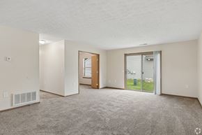 Blacklick apartment for rent - A spacious living room with a carpeted floor and a sliding glass door leading to a patio.