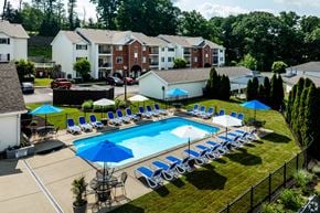 South Park Township condo for rent - A swimming pool surrounded by lawn chairs and umbrellas.