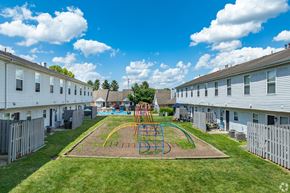 Lancaster apartment for rent - A playground with a swing set in the middle of a grassy area at River Valley Apartments in Lancaster, OH.