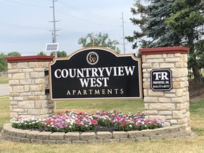 Hilliard apartment for rent - the sign for the countryview west apartments in front of a stone wall and flowers