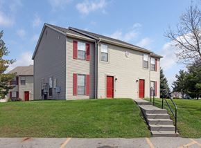 Delaware townhouse for rent - a yellow house with red doors on a green lawn