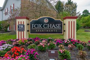 Marion apartment for rent - a sign for fox chase apartments in front of a garden of flowers