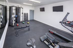 Denville apartment for rent - A gym with a variety of equipment including a treadmill, weights, and a bench press.