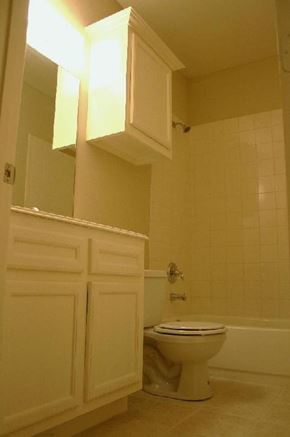 Houston apartment for rent - A white toilet sits in a bathroom with a white cabinet and a white door.