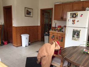 Boston apartment for rent - A man in a brown jacket is bending over a black mat in a kitchen.