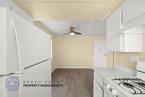 Hawthorne apartment for rent - A kitchen with white appliances and a logo for Beach Front Property Management.