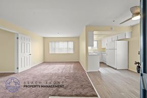 Hawthorne apartment for rent - A spacious room with a rug on the floor and a logo for Beach Front Property Management on the carpet.