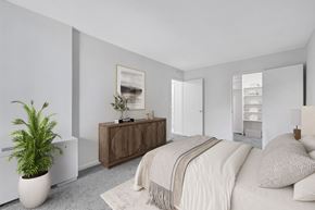 Washington apartment for rent - A bedroom with a bed, a plant, and a wooden cabinet.