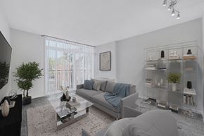 Washington apartment for rent - A modern living room with a grey couch, a glass coffee table, and a glass shelf with decorative items.
