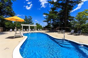 Washington apartment for rent - the pool is next to a patio with chairs and an umbrella