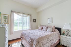 Palmetto apartment for rent - bedroom with large window, hardwood-style flooring, and model furnishings