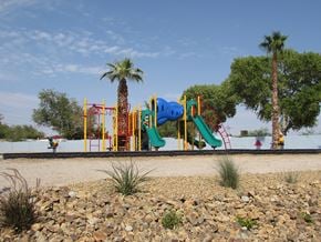 North Las Vegas apartment for rent - a playground in the middle of a dirt field with palm trees in the background