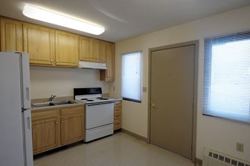Falcon Heights apartment for rent - A kitchen with wooden cabinets and white appliances.