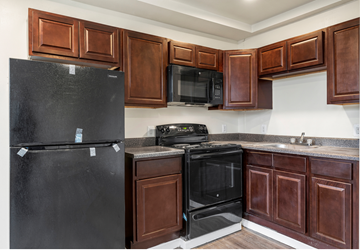 Philadelphia apartment for rent - A black refrigerator is in a kitchen with brown cabinets.