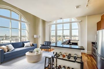 Baltimore apartment for rent - a living room with a blue couch and a kitchen with large windows