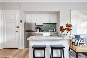 Chicago apartment for rent - a kitchen with white cabinets and a counter top with two stools