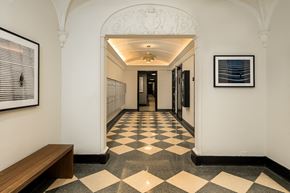 Chicago apartment for rent - a hallway in a building with a checkered floor and a bench
