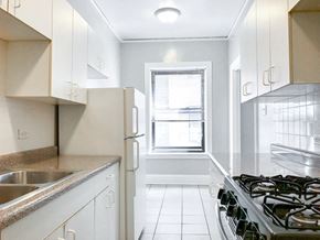 Chicago apartment for rent - an empty kitchen with white cabinets and a window