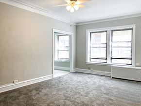 Chicago apartment for rent - an empty living room with two windows and a ceiling fan