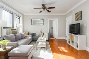 Chicago apartment for rent - A living room with a grey sofa, a white coffee table, and a ceiling fan.