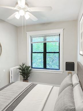 Chicago apartment for rent - A bedroom with a bed, a ceiling fan, and a window with a plant on the windowsill.