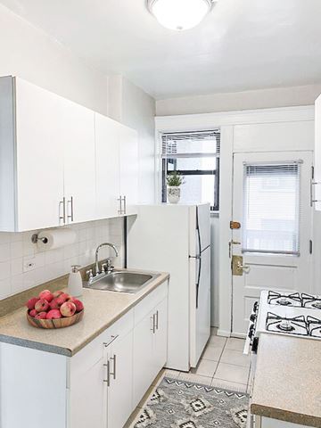 Chicago apartment for rent - A kitchen with white cabinets and a black and white rug.