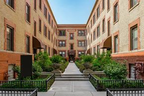 Chicago apartment for rent - a courtyard between two tall brick buildings with trees and plants