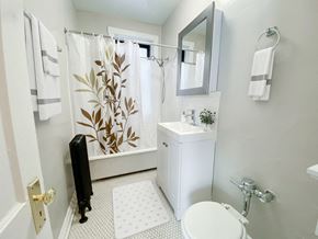 Chicago apartment for rent - A bathroom with a white toilet, sink, and shower curtain.