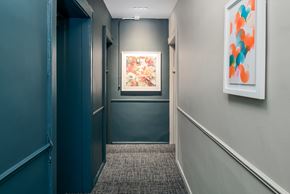 Chicago apartment for rent - A hallway with a painting on the wall and a carpeted floor.