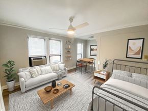 Chicago apartment for rent - A living room with a white couch, a wooden coffee table, and a bed with a white comforter.