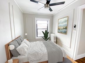 Chicago apartment for rent - A bedroom with a bed, a ceiling fan, and a painting on the wall.