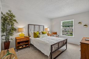 Farmington Hills apartment for rent - A bedroom with a large bed and a potted plant.
