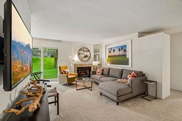 Farmington Hills apartment for rent - A living room with a grey couch, a yellow chair, and a painting of a landscape on the wall.