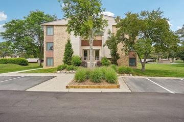 Farmington Hills apartment for rent - A building with a front yard and a parking lot in front.
