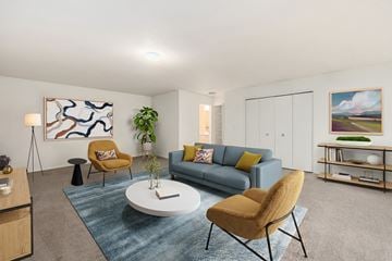 Farmington apartment for rent - A living room with a grey couch, a yellow chair, a white coffee table, and a painting on the wall.