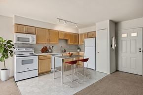 Farmington apartment for rent - A kitchen with a white fridge, white oven, and brown cabinets.