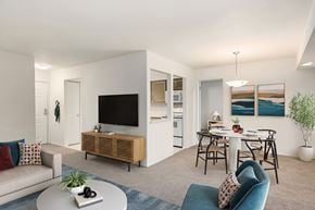 Farmington apartment for rent - A modern living room with a white sofa, a wooden cabinet, a white coffee table, and a dining table with chairs.