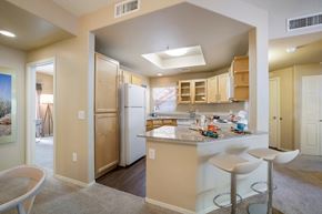 Tucson apartment for rent - a kitchen with a bar and stools and a refrigerator