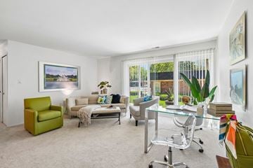 Farmington apartment for rent - A living room with a green chair and a glass table.