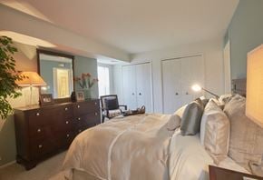 Farmington Hills apartment for rent - A bedroom with a large bed and a dresser with a mirror.