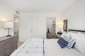 Novi apartment for rent - A bedroom with a large bed and a nightstand with a lamp.