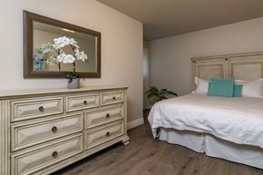 Kingston apartment for rent - A bedroom with a white bed and a dresser with a mirror above it.