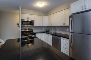 Amherstview apartment for rent - A kitchen with a black counter top and stainless steel appliances.