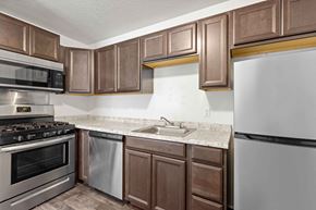 Fort Wayne apartment for rent - A kitchen with brown cabinets and a white refrigerator.