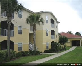 Oviedo apartment for rent - a yellow building with palm trees and a sidewalk